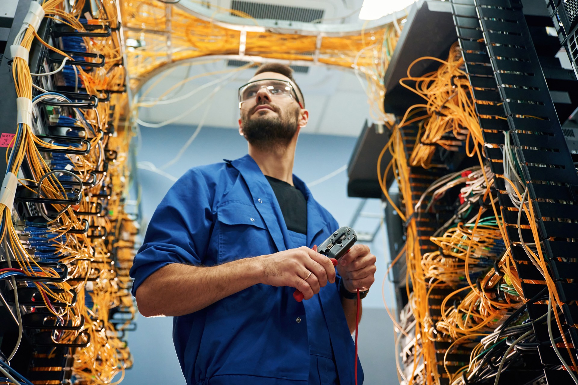 Cutting the wire. Young man is working with internet equipment in server room